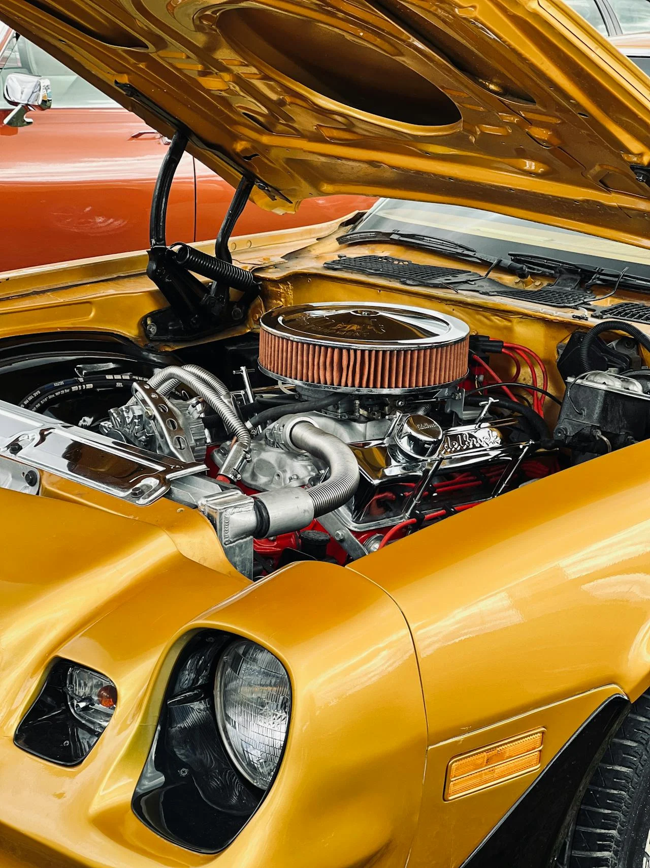 yellow sports car with hood up showing engine